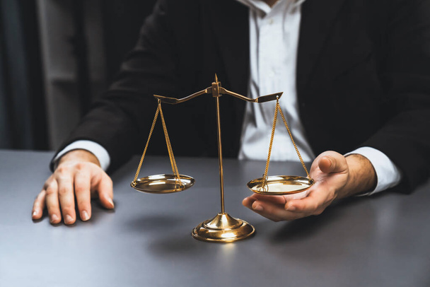 Lawyer in a black suit sits attentively on his office desk with a golden scale balance, symbol of legal justice and integrity, balanced and ethical decision making in the court of law. equility - Zdjęcie, obraz