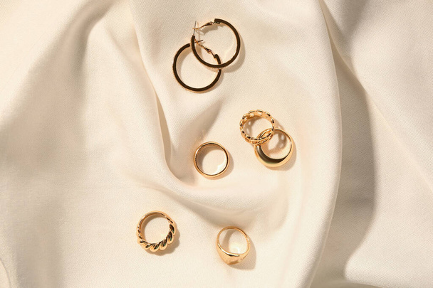 Gyönyörű fülbevalók és gyűrűk fehér szövet háttér - Fotó, kép