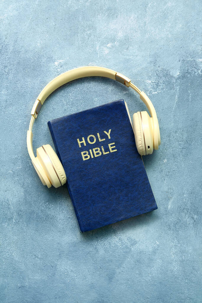 Santa Biblia con auriculares sobre fondo azul - Foto, imagen