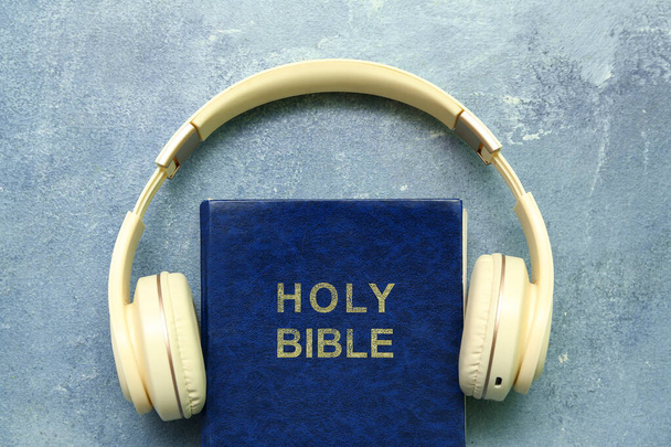 Santa Biblia con auriculares sobre fondo azul - Foto, imagen