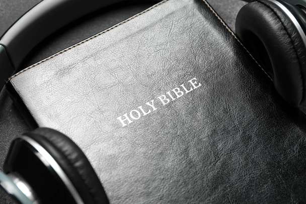 Holy Bible with headphones on dark background, closeup - Photo, image