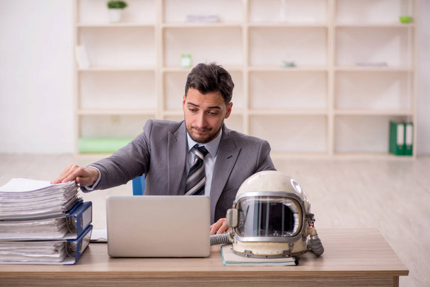 Young businessman employee wearing spacesuit at workplace - Foto, Imagem