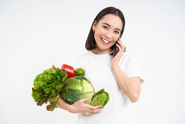 Счастливая здоровая женщина, звонки торговца, заказы органические овощи и улыбки, белый фон. - Фото, изображение
