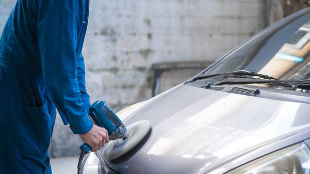 Close-up  man hand is using car polishing machine in repair mechanic painting shop  - Фото, изображение