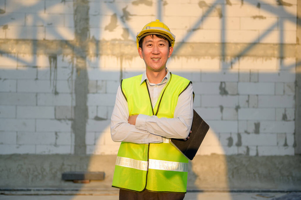 Portrait of An Asian Engineering man wearing safety helmet checking construction site analyzing about project progress  - Foto, Imagen