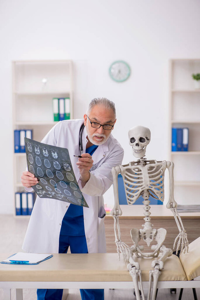 Old doctor examining skeleton at the hospital - Photo, Image