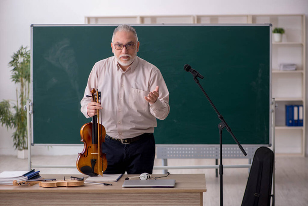 Viejo profesor tocando el violín en el aula - Foto, Imagen