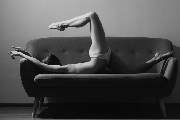 Flexible sexy woman. Home workout. Woman doing stretching up exercise at home on sofa - Foto, Bild