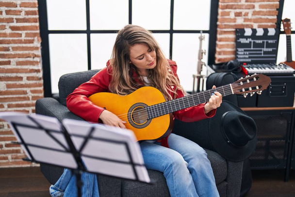 Молодая женщина-музыкант играет на классической гитаре в музыкальной студии - Фото, изображение