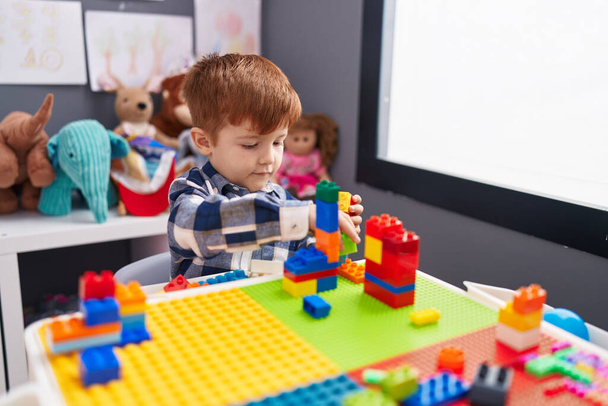 Adorable tout-petit jouant avec des blocs de construction assis sur la table à la maternelle - Photo, image