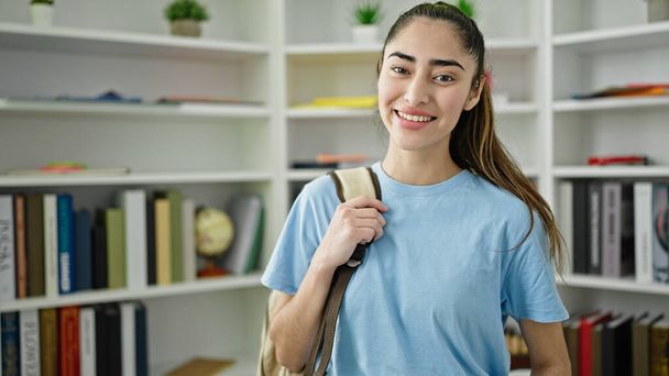 Молода красива студентка-іспанка посміхається впевнено стоїть в університеті бібліотеки
 - Фото, зображення