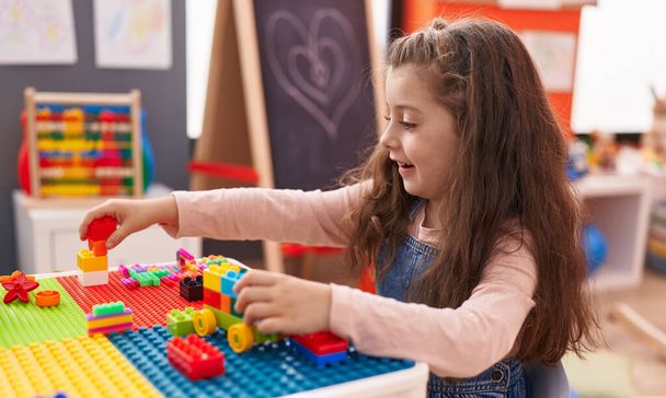 Adorável menina hispânica brincando com blocos de construção sentados na mesa no jardim de infância - Foto, Imagem