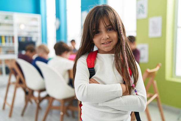 Imádnivaló spanyol lány diák mosolyog magabiztos álló karokkal keresztbe gesztus az osztályteremben - Fotó, kép