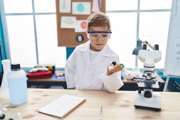 Adorabile studente ispanico ragazzo sorridente fiducioso in possesso di molecole in classe laboratorio - Foto, immagini
