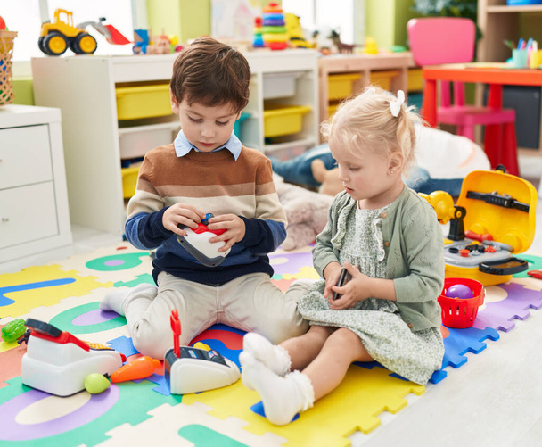 Adorable boy and girl playing supermarket game sitting on floor at kindergarten - Φωτογραφία, εικόνα