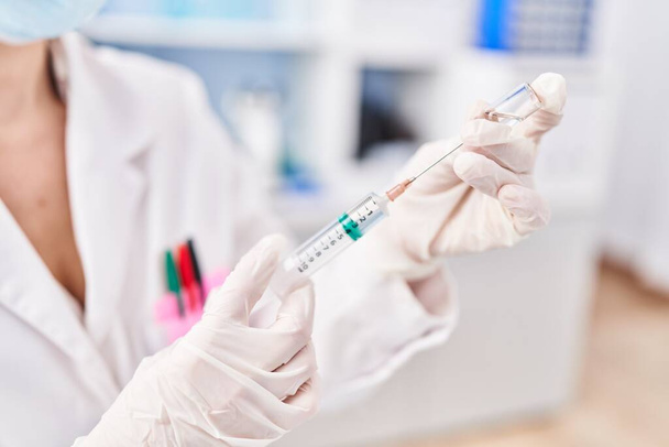 Молодая блондинка ученый держит ковид-19 вакцины в лаборатории - Фото, изображение
