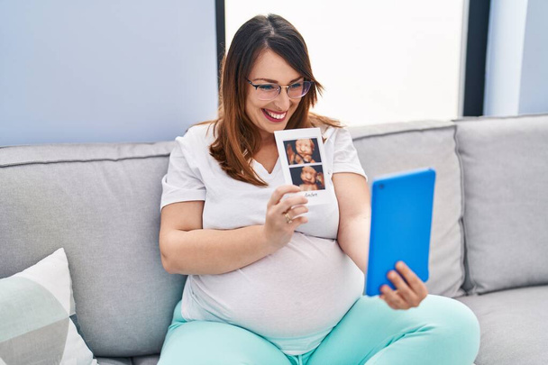 Young pregnant woman having video call holding baby ecography at home - Fotoğraf, Görsel