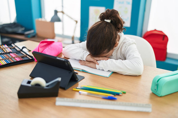 Entzückende hispanische Studentin mit Kopf auf Buch im Klassenzimmer gestresst - Foto, Bild