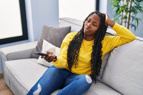 African american woman with boring expression watching tv at home - Foto, afbeelding