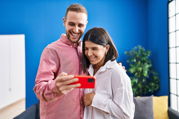 Ehepaar lächelt selbstbewusst mit Smartphone zu Hause - Foto, Bild