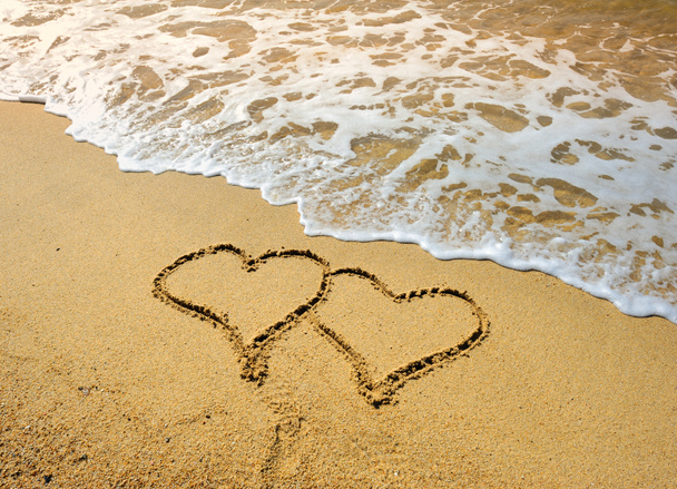 Kaksi sydäntä piirretty rannalla auringonlaskussa
 - Valokuva, kuva