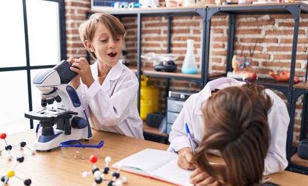 Adorable boys students using microscope writing notes at laboratory classroom - Photo, Image