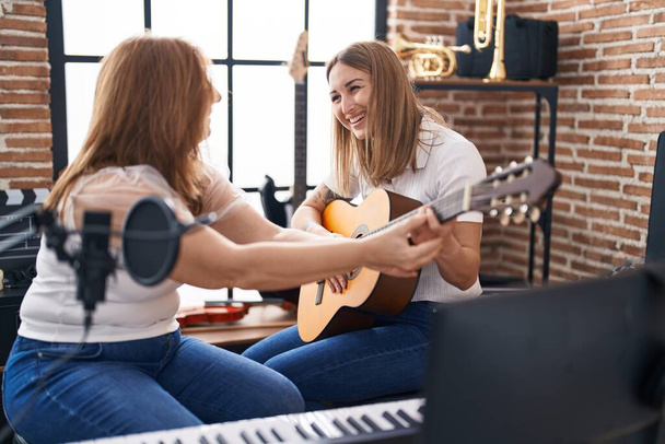 Mother and daughter musicians having spanish guitar class at music studio - 写真・画像