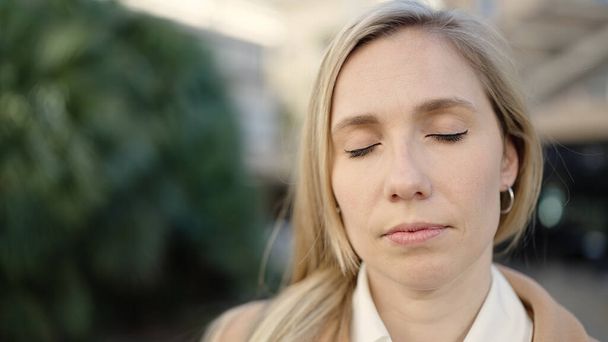 Young blonde woman breathing with closed eyes at park - Foto, Imagem