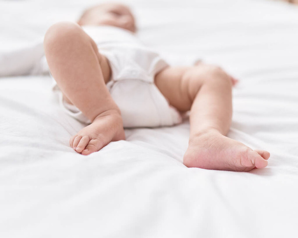 Adorable caucasian baby lying on bed at bedroom - Photo, image