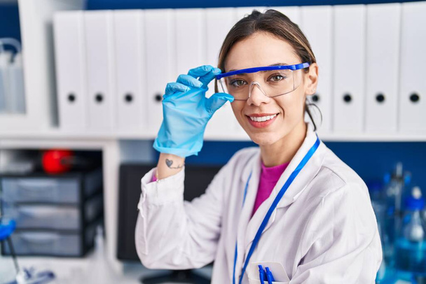 Молода красива іспаномовна жінка вчений посміхається впевнено стоїть в лабораторії
 - Фото, зображення