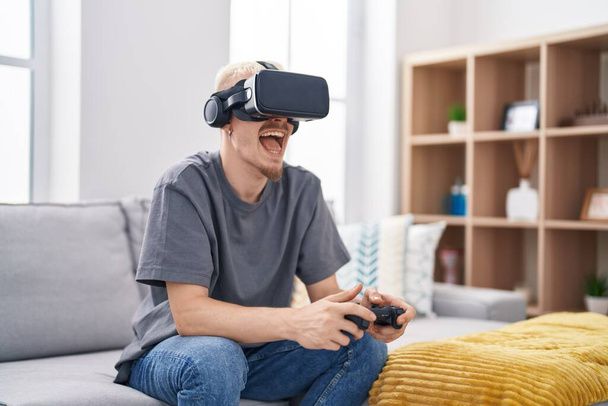 Young caucasian man playing video game using virtual reality glasses at home - Foto, Bild