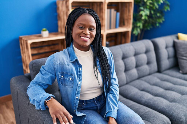 Afroamerikanerin lächelt selbstbewusst auf Sofa zu Hause - Foto, Bild
