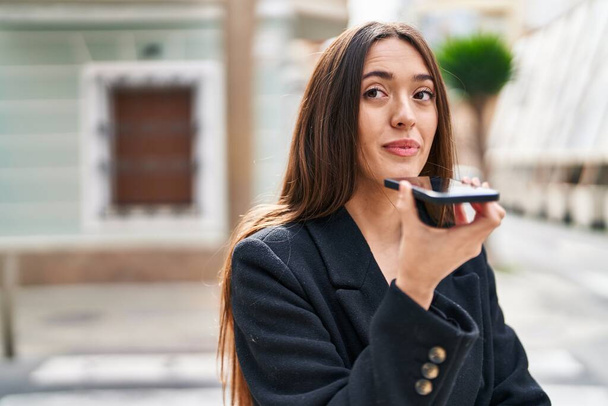 Genç, güzel, İspanyol bir kadın gülümsüyor ve caddede akıllı telefondan konuşuyor. - Fotoğraf, Görsel