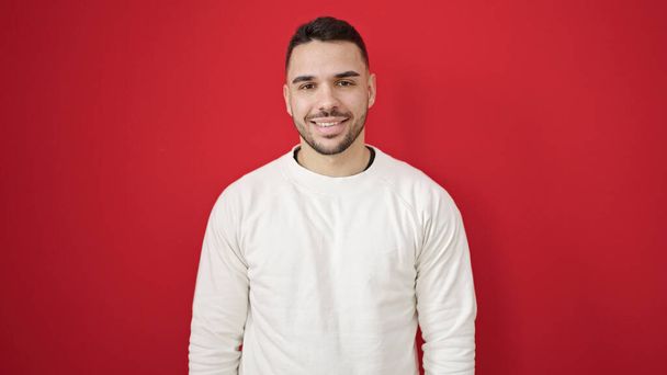 Young hispanic man smiling confident standing over isolated red background - Fotó, kép