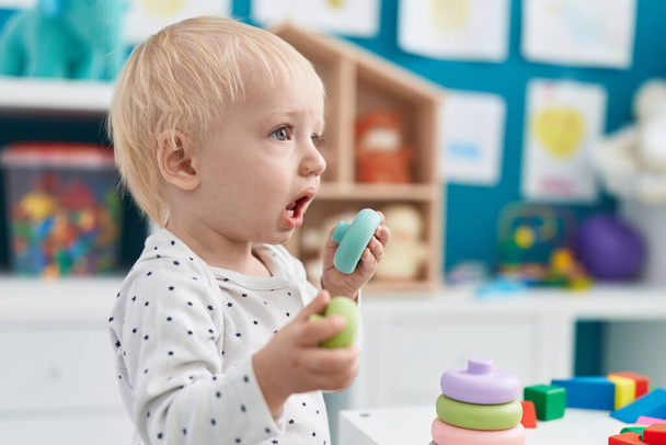 Adorable bambin blond jouant avec des jouets debout à la maternelle - Photo, image