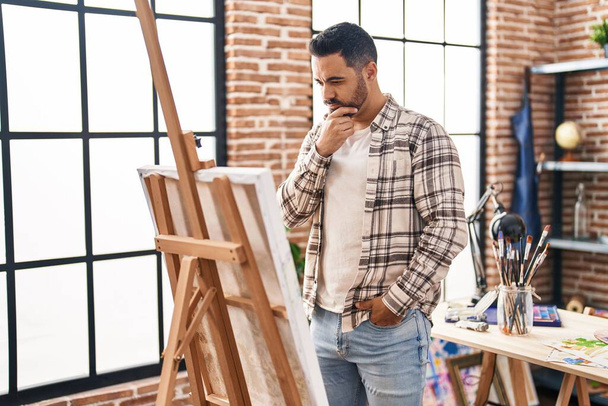 Young hispanic man looking draw with doubt expression at art studio - Photo, image
