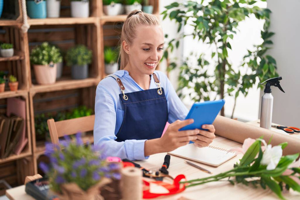 Young blonde woman florist smiling confident using touchpad at florist - Fotoğraf, Görsel
