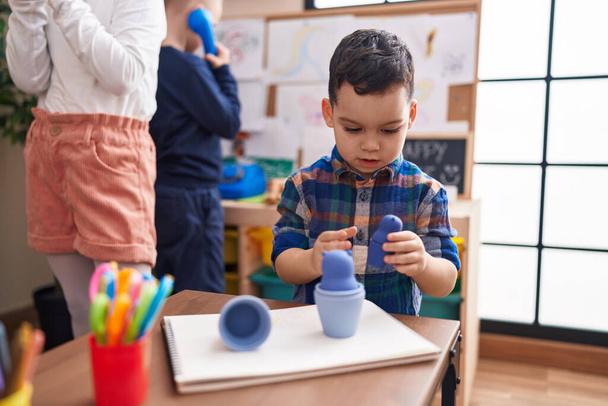 Adorable hispanic boy playing with toys sitting on table at kindergarten - Photo, Image