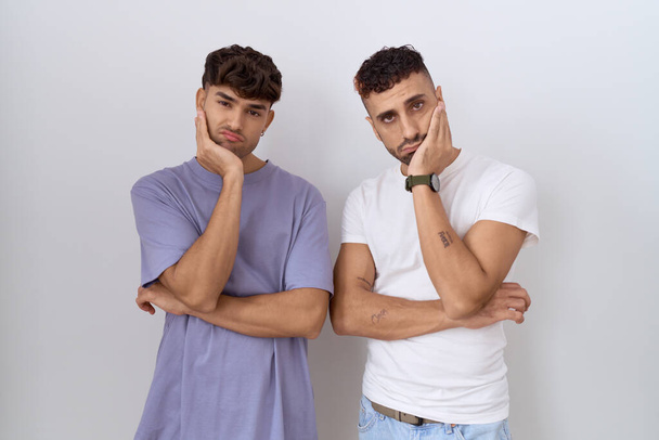 Homosexual gay couple standing over white background thinking looking tired and bored with depression problems with crossed arms.  - 写真・画像