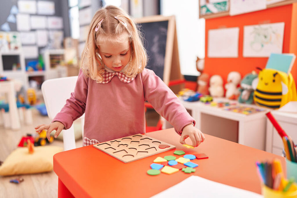 Очаровательная блондинка, играющая с математическими головоломками в детском саду - Фото, изображение