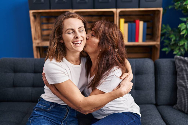 Due donne madre e figlia che si abbracciano baciandosi a casa - Foto, immagini