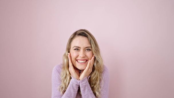 Young blonde woman standing with surprise expression over isolated pink background - Photo, Image