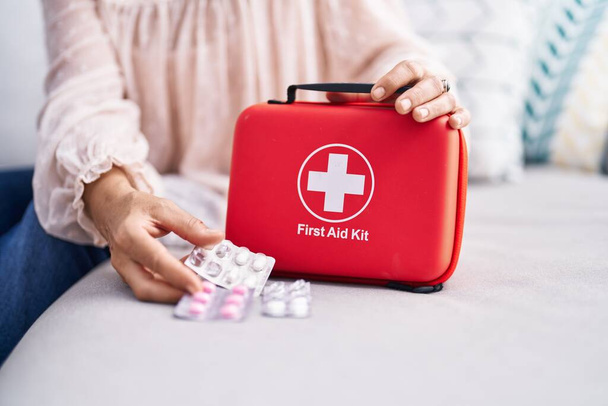 Middle age grey-haired woman holding pills and first aid kit at street - Foto, imagen