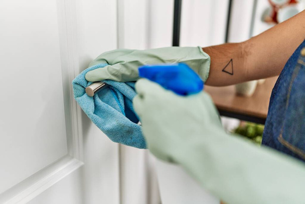 Fiatal gyönyörű spanyol nő takarítás ajtó gomb otthon - Fotó, kép