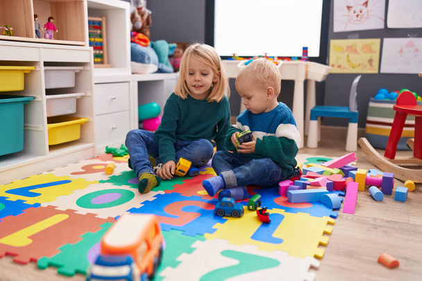 Adorável menino e menina brincando com carros brinquedo sentado no chão no jardim de infância - Foto, Imagem