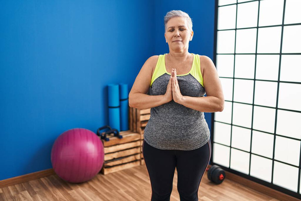 Middle age woman training yoga at sport center - Zdjęcie, obraz
