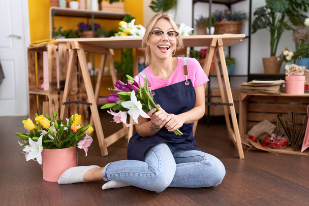 Jeune femme caucasienne travaillant à la boutique de fleuriste assis de plancher célébrant fou et étonné pour le succès avec les yeux ouverts hurlant excité.  - Photo, image