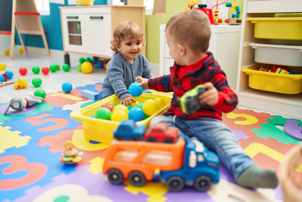 Adorable boys playing with balls and car toy sitting on floor at kindergarten - Photo, Image