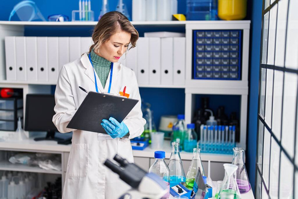 Young woman scientist writing report at laboratory - Foto, afbeelding