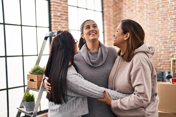 Three woman smiling confident hugging each other at new home - Foto, Imagen